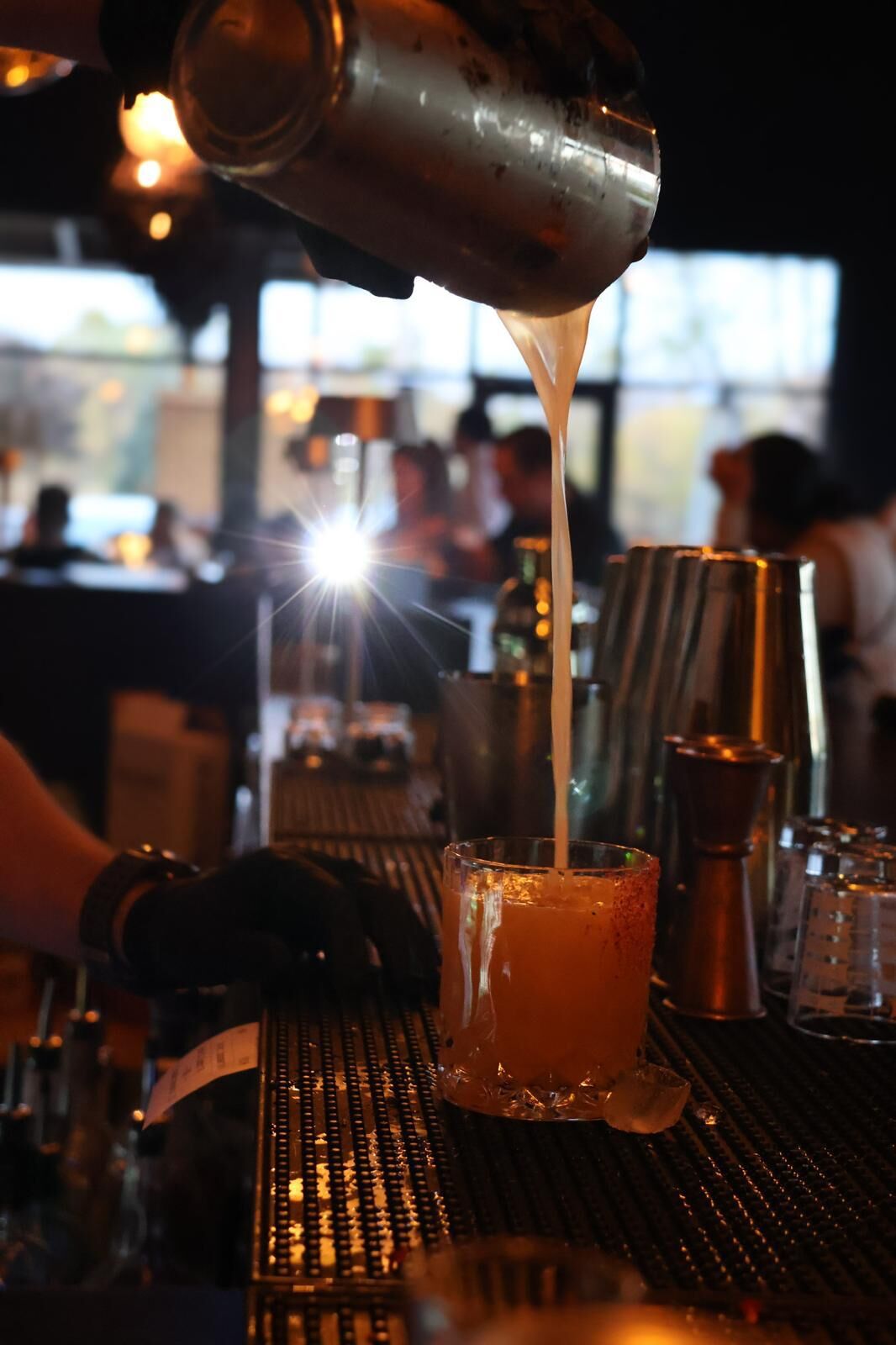 A cocktail strained from the tin into a rimmed crystal glass